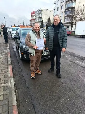 Cursant admis, cu foaia de examen în mână, lângă mașina școlii