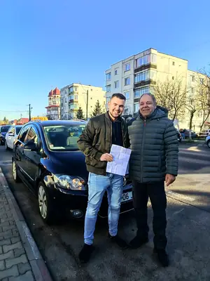 Cursant admis, cu foaia de examen în mână, lângă mașina școlii