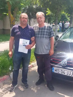 Cursant admis, cu foaia de examen în mână, lângă mașina școlii