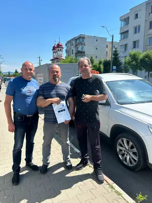 Cursant admis, cu foaia de examen în mână, lângă mașina școlii