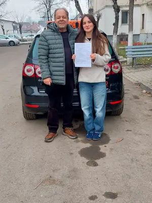 Cursant admis, cu foaia de examen în mână, lângă mașina școlii