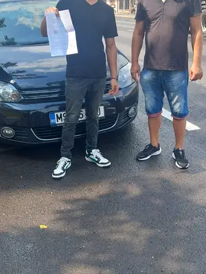 Cursant admis, cu foaia de examen în mână, lângă mașina școlii