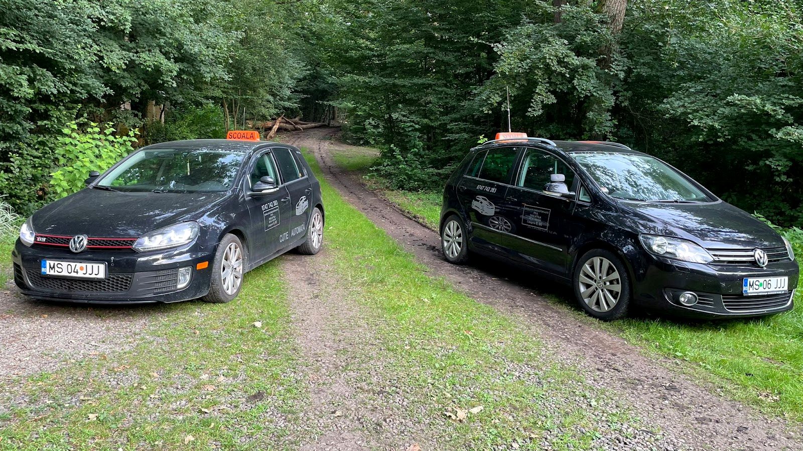 Cele două mașini ale școlii, un Golf cu cutie automată și un Golf Plus cu cutie manuală, cu tăblițele ȘCOALĂ pe plafon