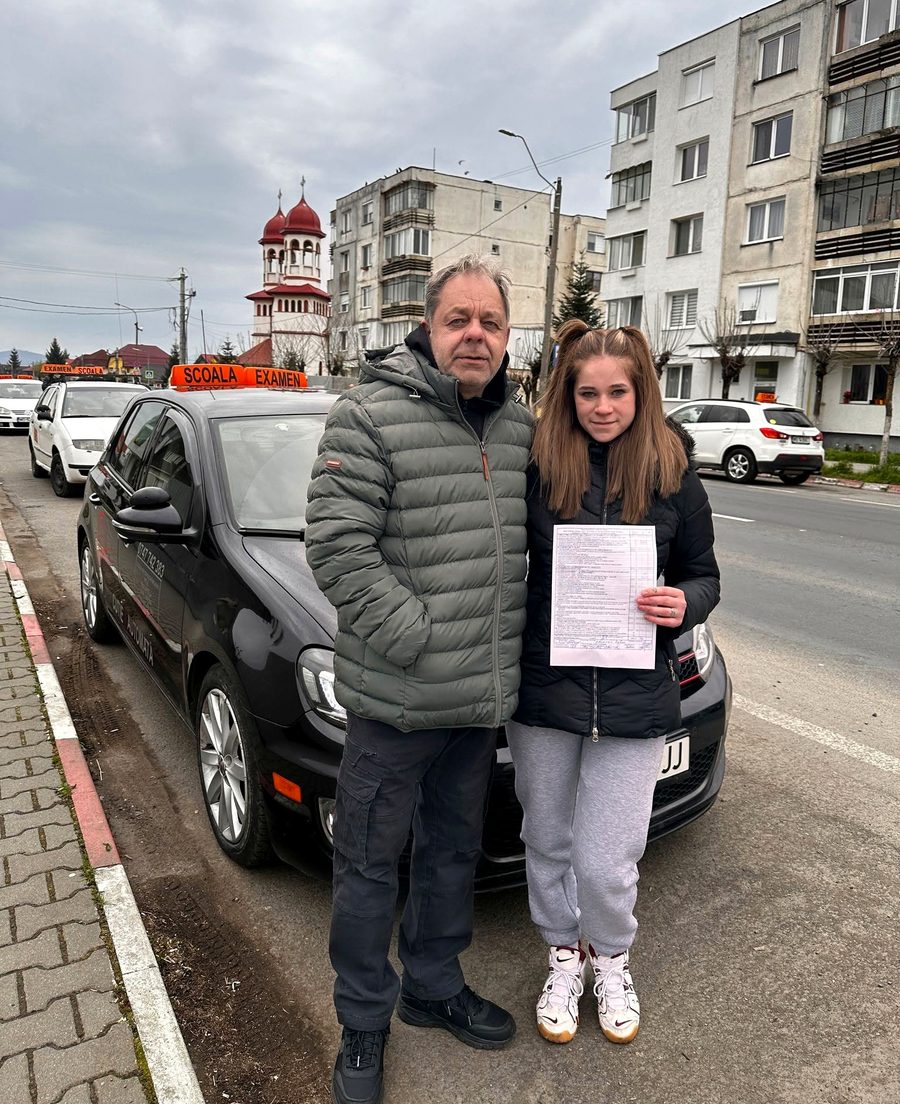Alexandru Salati, instructor auto în Reghin, lângă mașina școlii cu o cursantă admisă